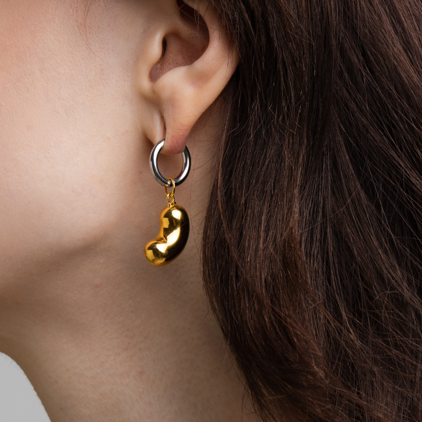 model wearing bean pendant made of gold-plated silver with an earring