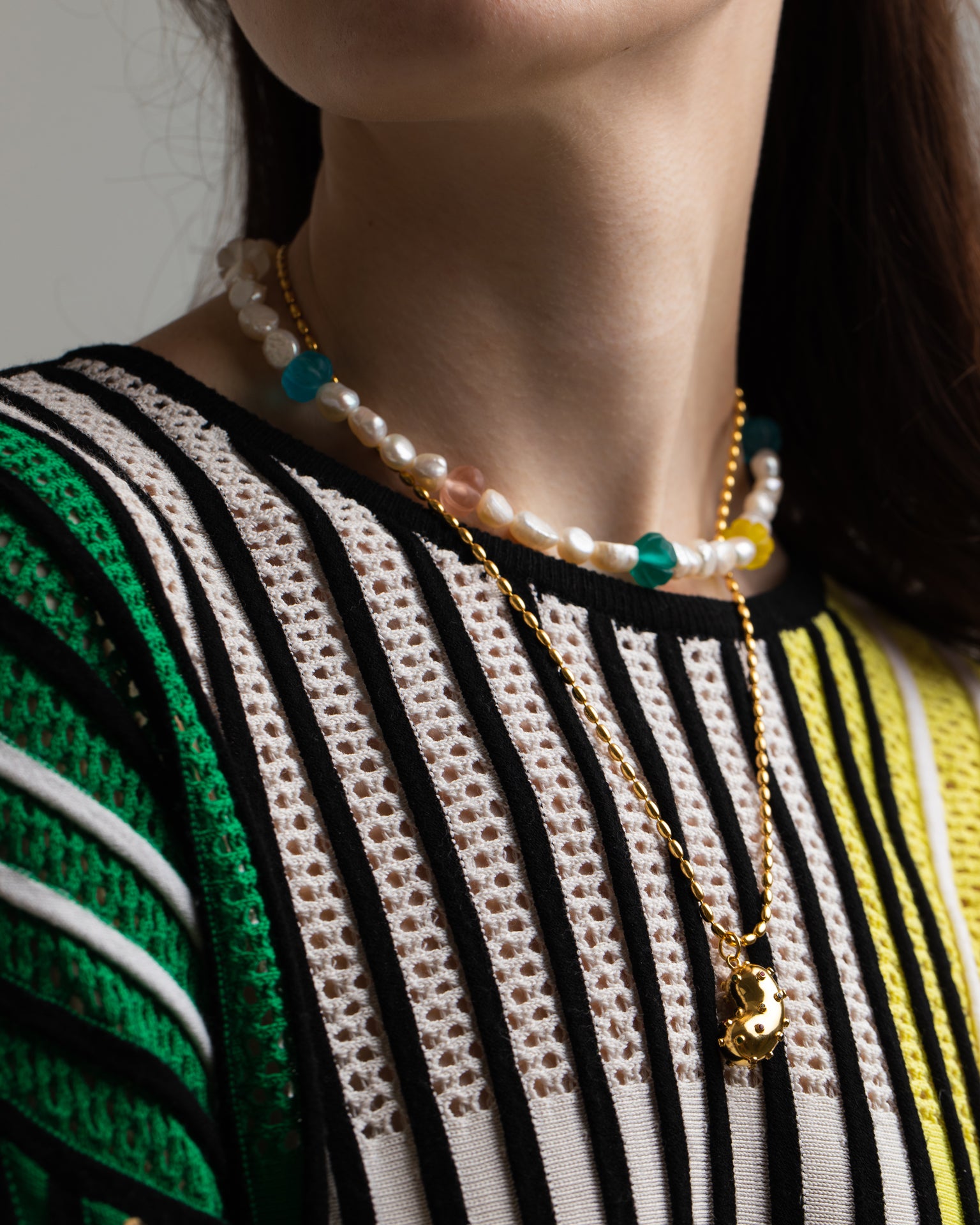 Model wearing golden Oval chain with a bean pendant. Gold plated silver