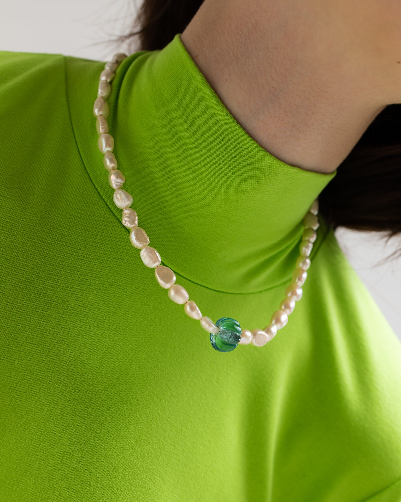 Model wearing necklace made of an old glass bead, freshwater pearls and 925 rhodium plated silver