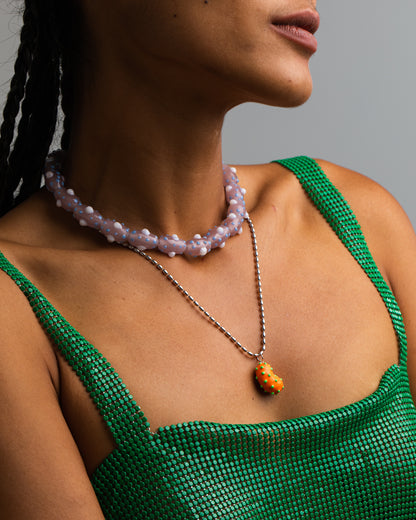 Model wearing A silver bean pendant enveloped in lush orange enamel, accented with playful green dots