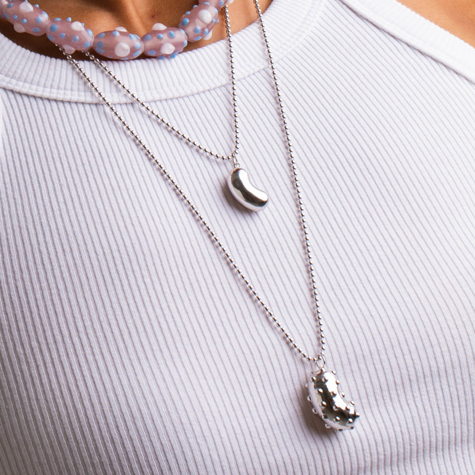 model wearing a bean pendant made of rhodium-plated silver